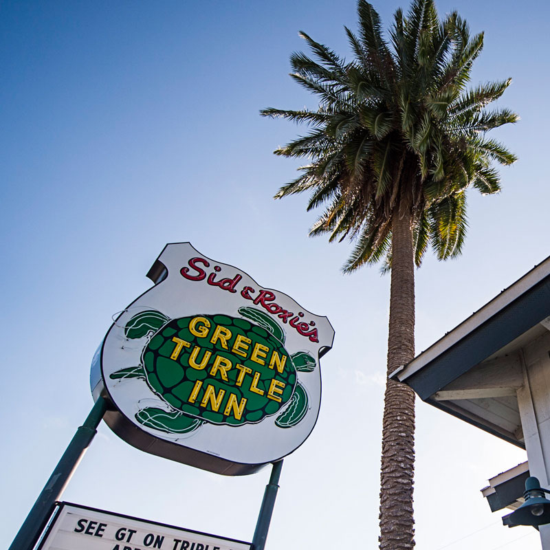 Signage outside Green Turtle Inn with palm tree