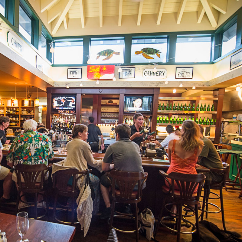 A bartender pours wine at a full bar